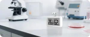 Termohigrómetro Elitech TM-2TH colocado sobre una mesa de laboratorio junto a material y equipos de laboratorio para monitorear las condiciones ambientales.